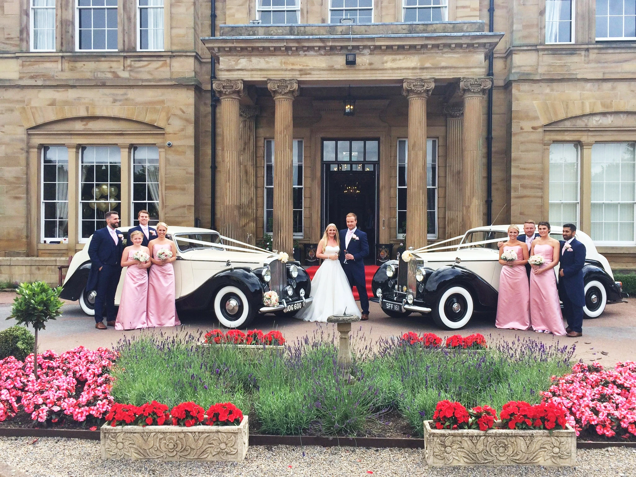 Bride and groom in front with their bridesmaids, best men and their classic cars standing for the photoshoot