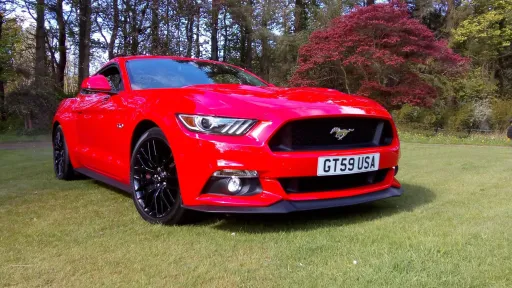 Side View of an American Red Ford Mustang on Green Grass