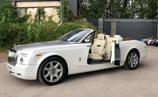 White Rolls-Royce Convertible with roof and foor open showing cream leather interior waiting for Bride and Groom
