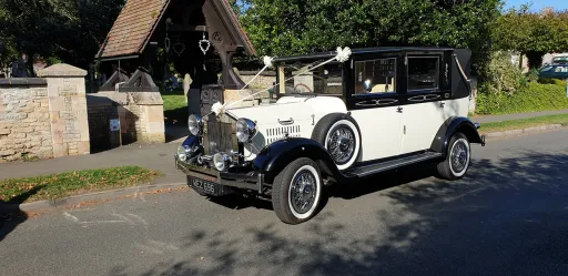Black & White Vintage Limousine Imprial Wedding Car decorated with white ribbons in front of church in Lincoln