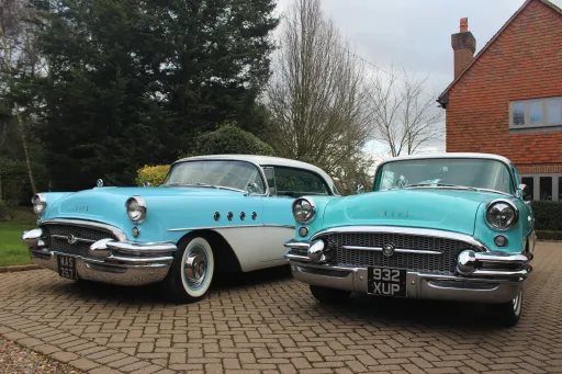 Two side-by-side Classic American Buick showing front chrome bumper and whitewall tyres