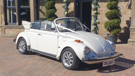 Convertible Classic VW Beetle with roof open in front of wedding venue in Durham decorated with White Ribbons