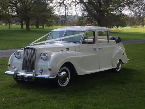 7-seater Classic Austin Princess Limousine with White Ribbons waiting for Bride and Groom on green field in Manchester Park