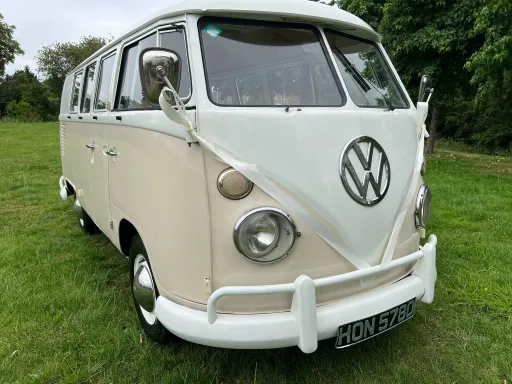 White and Cream VW splitscreen Campervan with White Ribbons on the front in a park in Witlshire