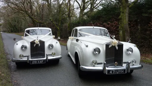 Two White Rolls-Royce next to each others decorated with Ivory Ribbons in the Wiltshire countryside