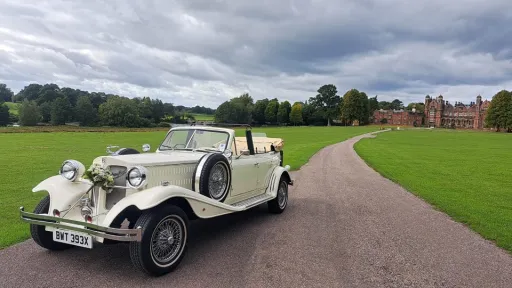 Froint View of Convertible Beauford Wedding Cars with Floral Decoration on Front Grill with Manchester Wedding Venue showing in background