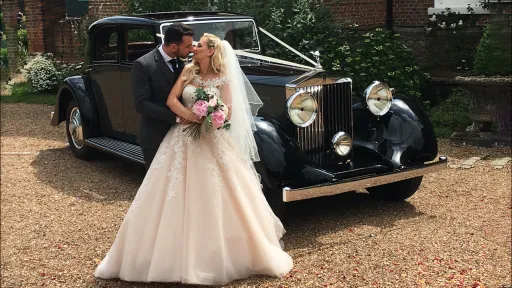 Black & Grey Vintage 1930s Rolls-Royce phantom in Leicestershire with Bride and Groom in front of the car kissing