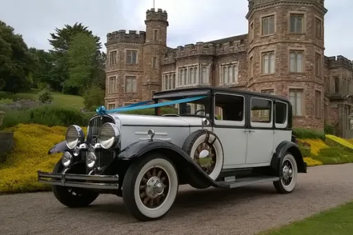 Vintage Black & White Car with Turquoise Blue Ribbons on front of the car waiting at Devon Wedding Venue