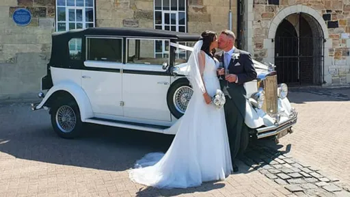Newly Wed Couple standing by their vintage car in front of the wedding venue in Durham