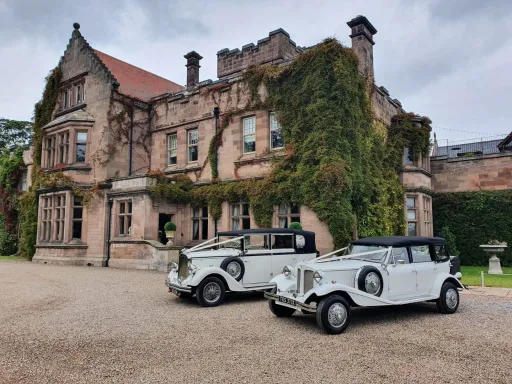Two Vintage Cars decorated with White Ribbons in front of wedding venue in Northumberland
