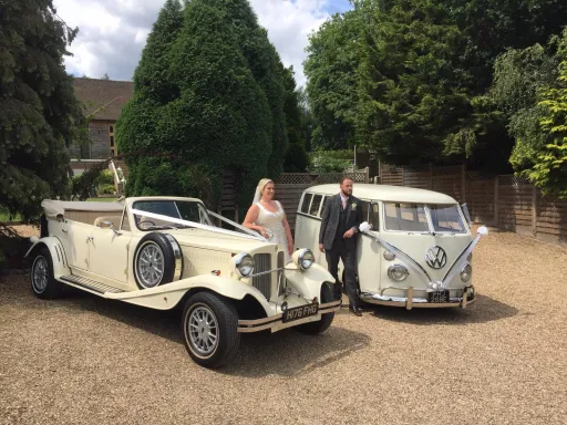Classic VW Campervan and a Vintage Beauford at wedding venue in West Sussex. Both decorated with White Ribbons and Bows. Bride and Groom standing next to the cars.