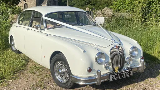 Ivory Jaguar Mk2 with V-Shape White Ribbon on it's bonnet waiting for happy couple by church in  Ceredigion