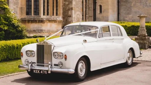 Classic Rollls-Royce Silver Cloud with traditional white ribbon in front of church in Monmouthshire