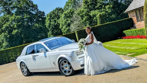 Front View of a Modern White Rolls-Royce Phantom with Bride wearing a White wedding dress posing for photo.