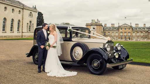 Vintage Rolls-Royce white White ribbons in Bedfordshire with Bride and Groom holding hands in front of the vehicle