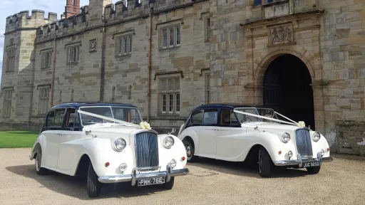 Two Classic Austin Princess Limousine outside wedding vneue in East sussex both decorated with white ribbons and White bow on top of the chrome grill