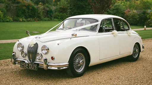 Ivory Classic Jaguar in Northamptonshire decorated with White ribbons going accross the bonnet