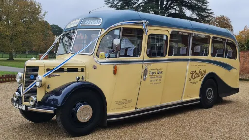 Side view of a Single Decker Classic Bedford Bus in Cream and Blue on hire in Surrey. Bus is dressed with Blue Ribbons on the front bonnet.