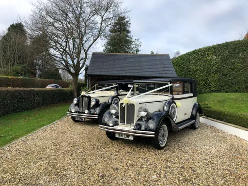 Two matching vintage regent convertible outdside wedding venue in East Sussex. Both vehicles are dressed with White Ribbons, Ivory Coloured with Black wheel arches