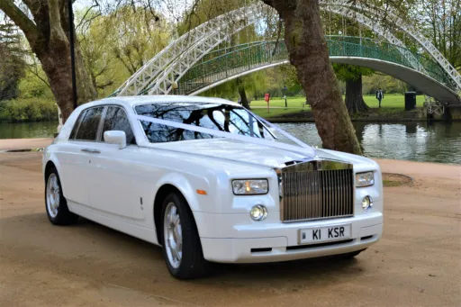 White Modern Rolls-Royce waiting for Bride and Groom in a park in Northamptonshire. Car is decirated with White Ribbons