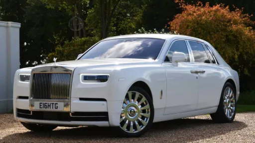 Front Side view of Modern Rolls-Royce Phantom 8 in white. Wheels are turned to show the chrome