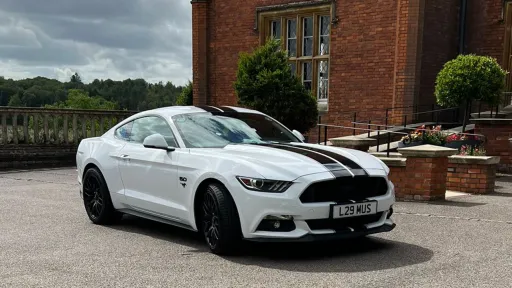 American Ford Mustang in white with Black stripe accross the length of the car waiting for groom outside venue in Bedfordshire