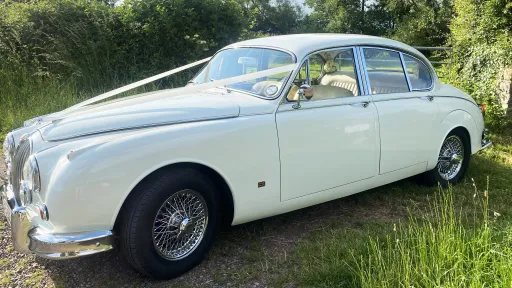 Classic Jaguar Mk2 with White Wedding ribbons taken from the side showing the chromed spokes wheels and cream leather interior