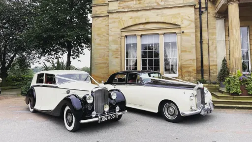 Two Black & Ivory Classic Rolls-Royce decorated with white ribbons waiting for Bride and Groom in front of wedding venue in South Yorkshire