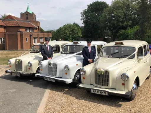 Three Classic Taxi Cabs decorated with Ribbons and flowers on front grill with their chauffeurs standing by the cars.  chauffeurs are wearing dark grey suit and chauffeur's hat
