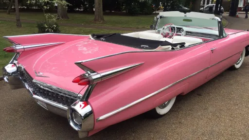 Rear view of Pink cadillac showing Chrome bumper and tail. Roof is open showing the cream leather interior