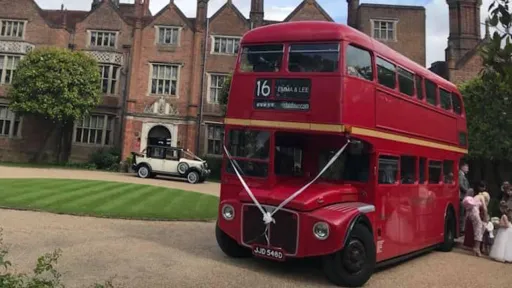 Vintage routemaster Red bus at a venue in Hertfordshire decorated with White Ribbons at the front of wedding venue