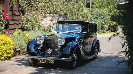 Blue Convertible Vintage Rolls-Royce Wedding car in Gloucestershire with white ribbons and chauffeur driving the vehicle