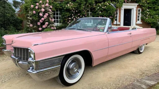 Pink classic convertible cadillac. Roof is open showing the burgundy  interior leather.
