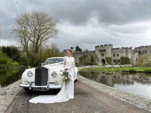 White classic Rolls-Royce Silver Cloud in front of Allington Castle in Kent with Bride standing in front of the vehicle