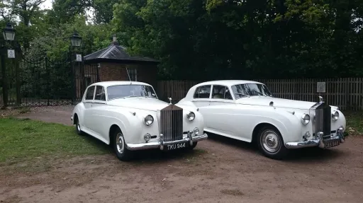 Two matching white classic rolls-royce side-by-side waiting for bride to come out of her house
