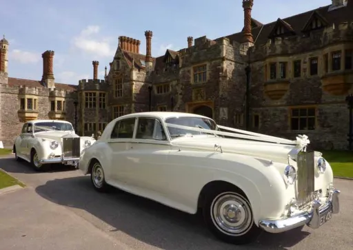 Two Classic Rols-Royce Silver Cloud in Ivory with White Ribbons on the Bonnet in front of Rhinefield House Hotel in New Forest