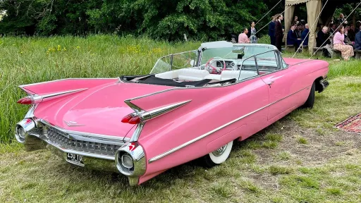 Rear view of a Pink American Cadillac showing chrome bumper. The roof is open showing the White Leather interior.