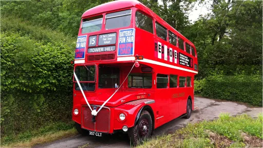 Vintage Red Routemaster Bus with white ribbons and vintage advertising on its side