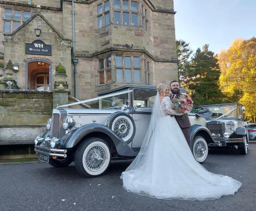 Two Weddings Cars in front of Weston Hall in Staffordshire. both bride and groom are posing in front of the cars for photos.