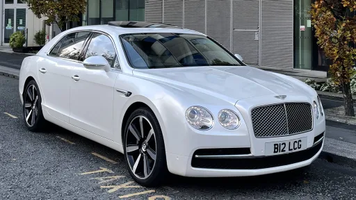 Side view of White Modern Bentley showing the big imposing Bentley Alloy. Car waiting on the side road for the bride