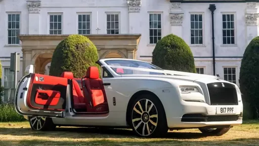 White convertible Rolls-Royce Dawn with White Ribbon. Door is opened showing a Deep Red leather interior