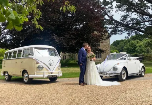 Classic VW campervan and Beetle at wedding venue in Rutland with beride and groom standing in the middle of the car.