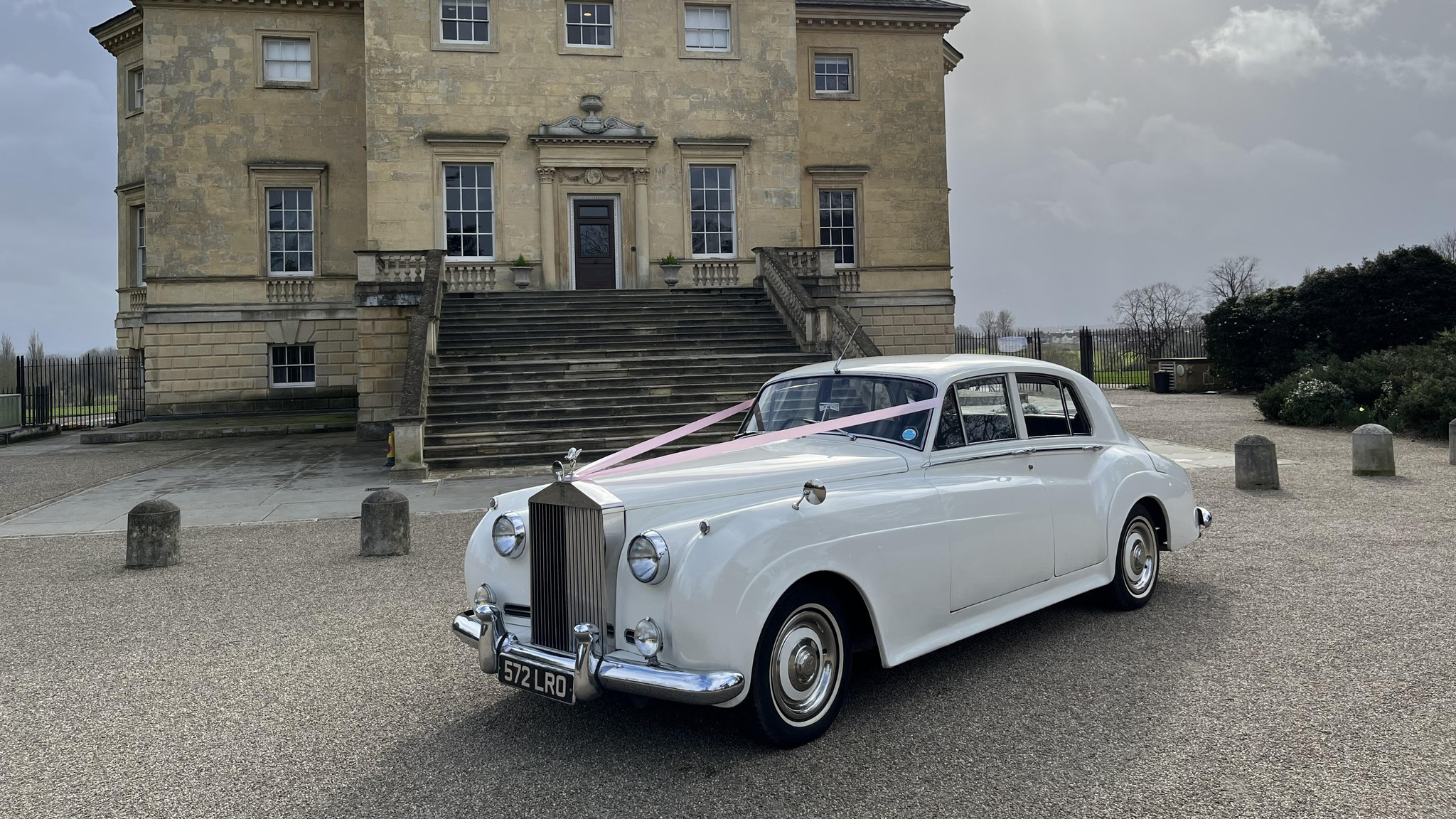Classic Rolls-Royce Silver Cloud in white with pale pink wedding ribbons on top of the bonnet