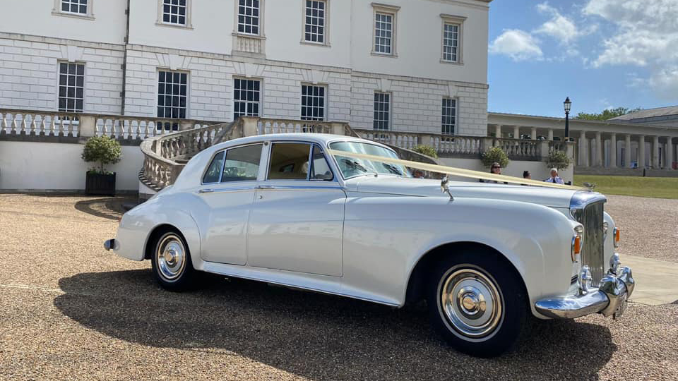 White Classic Bentley S3 dressed with ivory ribbons in front of the Queen's House in London