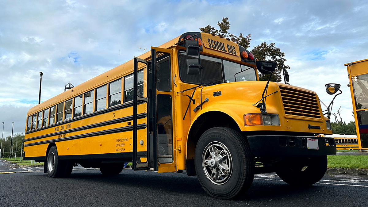 A classic american yellow bus with its front double door open.