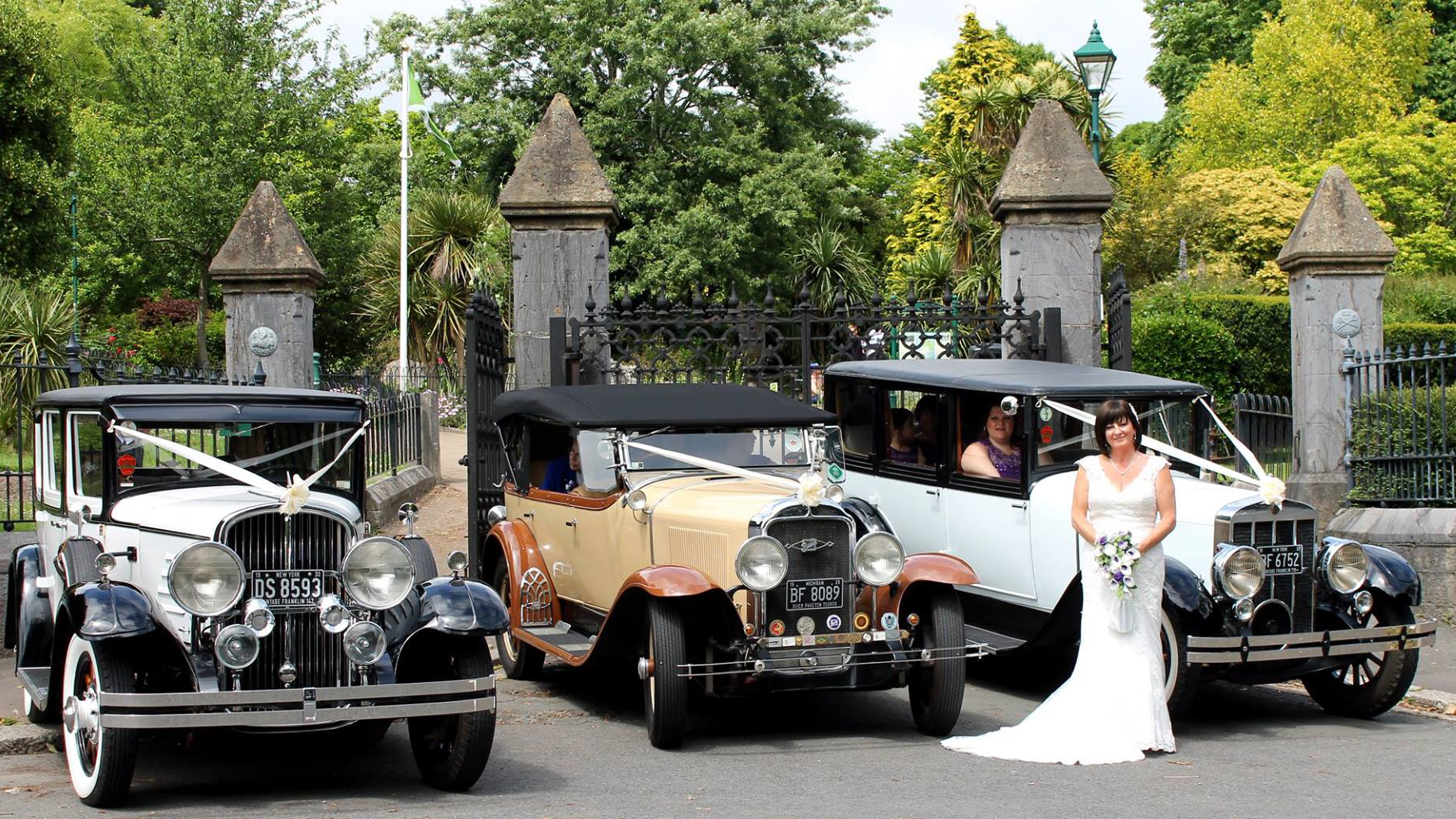 Two vintage wedding cars decorated with white ribbons at a local Bude wedding. Both vehicles are parked side-by-side