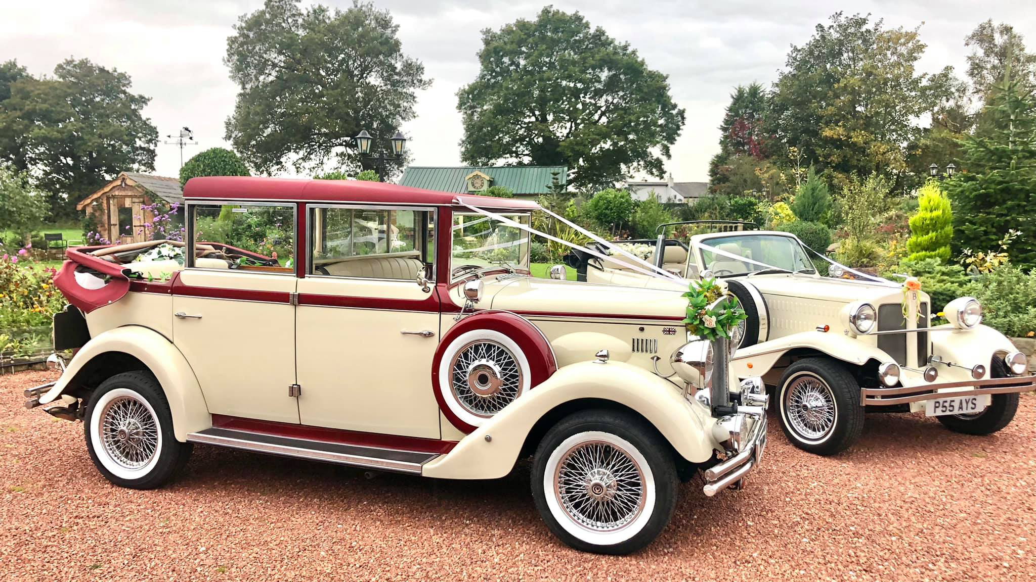 Two vintage wedding cars decorated with white ribbons at a local Chester wedding. Both vehicles are parked side-by-side