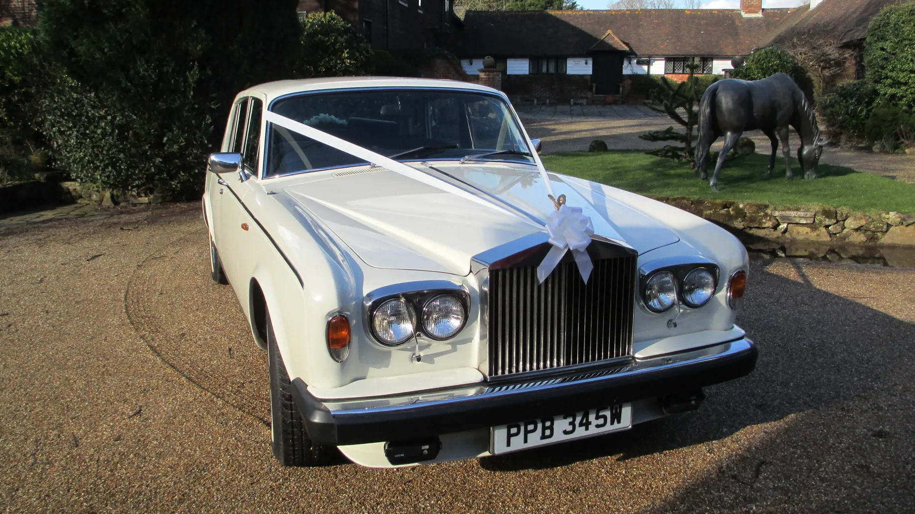 Classic Rolls- Royce Silver Shadown in white decorated with ribbons parked in front of a local Newquay wedding venue.