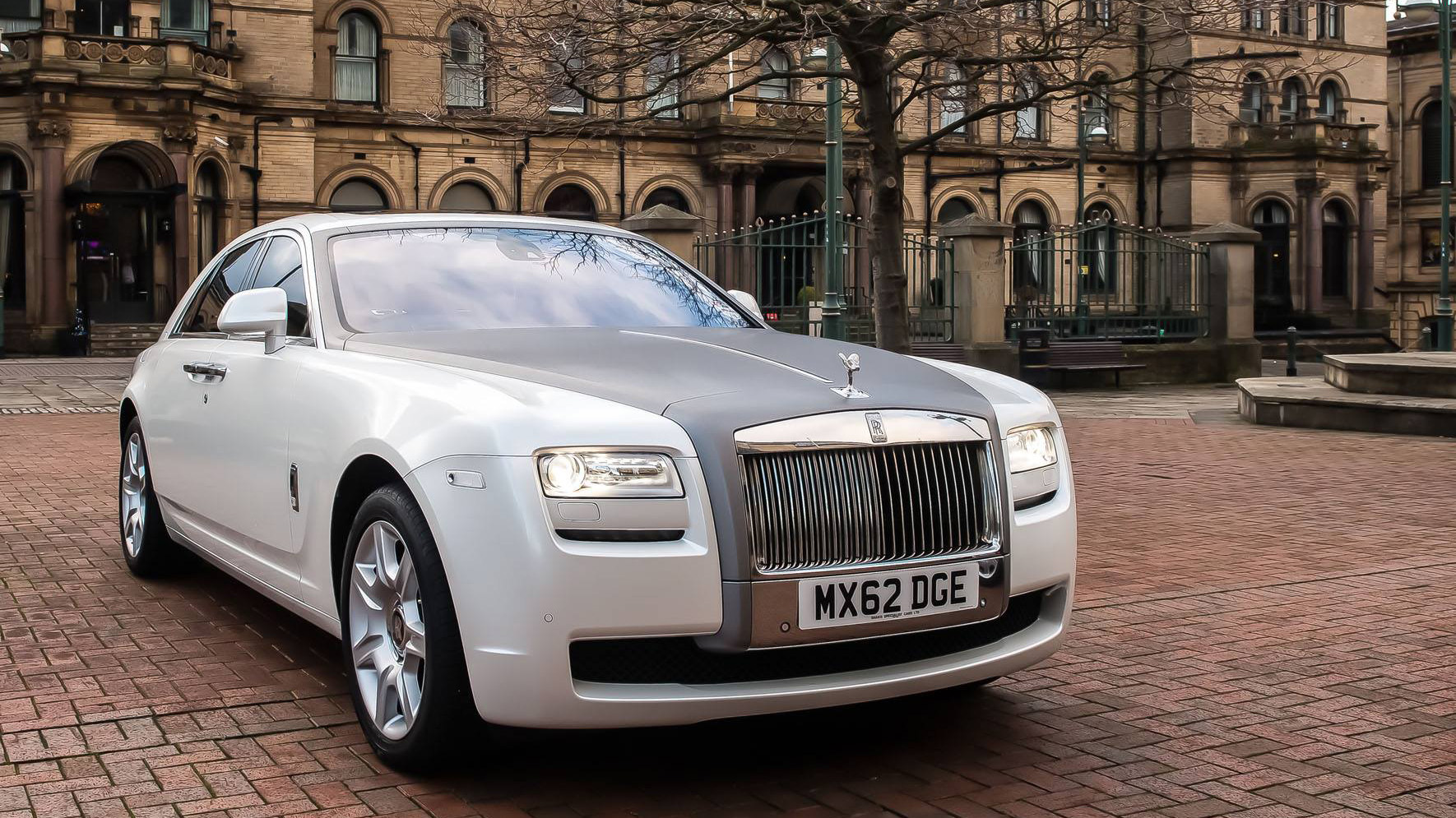 Rolls-Royce Ghost in white with Silver Bonnet, headlights are turned on and spirit of ecstasy is showing.