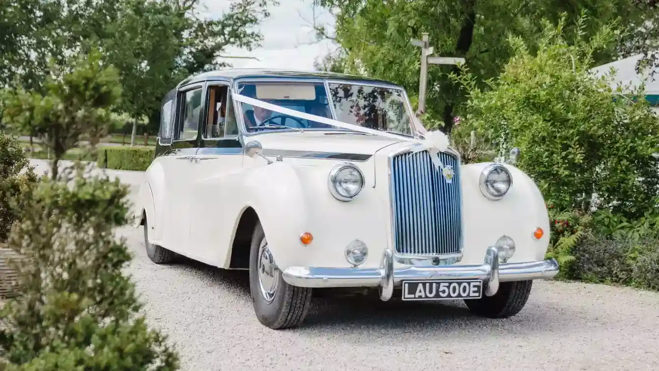 Ashby-de-la-Zouch-based austin Princess Limousine in white with black roof with chauffeur driving the vehicle in the wedding venue.
